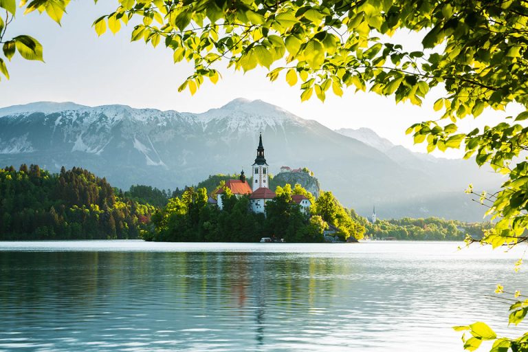 View across Lake Bled to the island church, clifftop castle and Mount Stol in all it's spring glory, Slovenia.